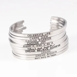 Detail shot of stacked silver stainless steel cuff bracelets with inspirational engravings