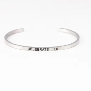 Close-up detail of stainless steel cuff bracelet with "CELEBRATE LIFE" engraving.