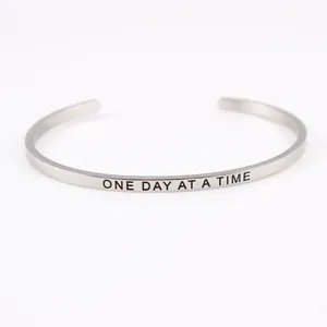 Close-up of silver stainless steel cuff bracelet with ONE DAY AT A TIME engraving