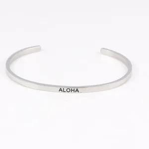 Detailed view of a minimalist 3.2mm titanium steel open bangle with ALOHA engraving