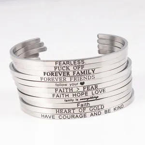 Close-up of stainless steel cuff bracelets with various engraved inspirational quotes.