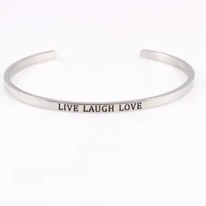 Close-up of "LIVE LAUGH LOVE" engraving on a silver stainless steel cuff bracelet.