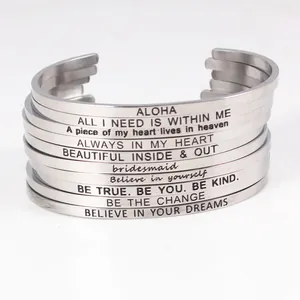Détail de bracelets joncs en acier inoxydable empilés avec des mantras inspirants.