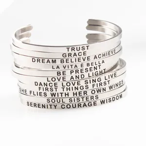 Stack of minimalist stainless steel cuff bracelets with inspirational engraved quotes