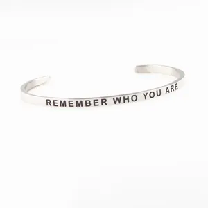 Detail of silver stainless steel cuff bangle with REMEMBER WHO YOU ARE engraving