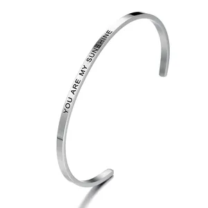 Close-up detail of stainless steel cuff bracelet with 'You are my sunshine' engraving.