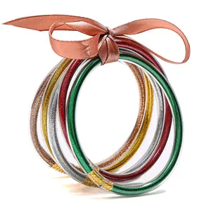 Multi-layered glitter filled silicone bracelets set with a ribbon bow on white background.