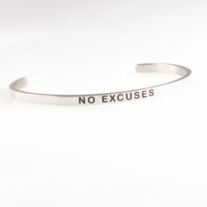 Close-up detail of the 'NO EXCUSES' engraved slogan on a stainless steel silver cuff bracelet