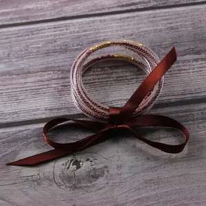 Detail of five-layer silicone jelly bangles with reddish-brown beads and ribbon.
