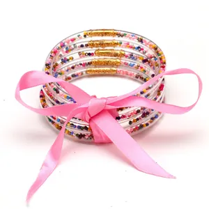 Primo piano di 5 bracciali jelly con perline colorate e un elegante fiocco di nastro rosa