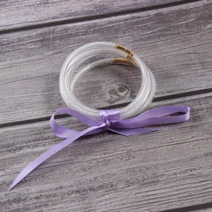 Close-up of five silver glitter-filled silicone jelly bangles with a purple ribbon bow.