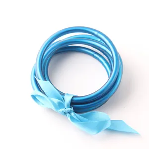 Close-up view of three blue silicone tube Buddhist bangles tied with a matching satin ribbon.
