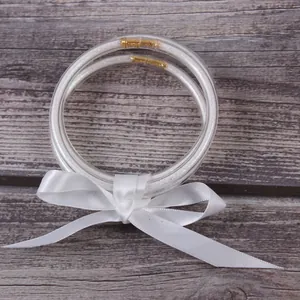 Détail rapproché de joncs en silicone pailleté à trois couches avec un nœud en satin blanc