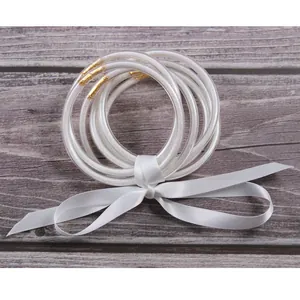 Detailed close-up of 7-piece white glitter jelly bangles tied with a silk ribbon bow