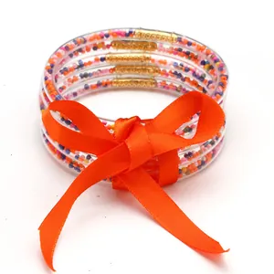 Set di cinque braccialetti in silicone con perline colorate e un fiocco arancione.