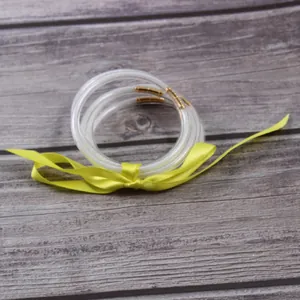Macro detail view of three shimmering glitter silicone jelly bangles with a yellow ribbon bow
