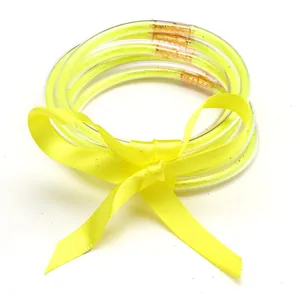 Set of five yellow glitter silicone jelly bangles tied with a matching silk ribbon bow