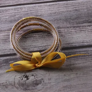 Close-up of five-layer silicone jelly bangles with golden seed beads and ribbon.