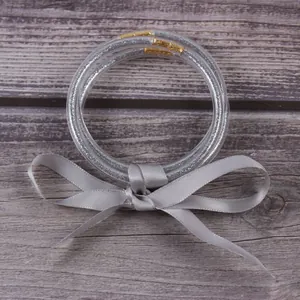 Gros plan de trois bracelets en silicone pailleté argent avec un nœud en ruban satin