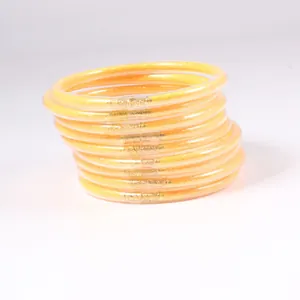 Close-up of yellow PVC jelly bangles filled with sparkling gold glitter, set of 12.
