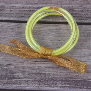 Detailweergave van vijf gele met glitter gevulde siliconen armbanden met een gouden lintje