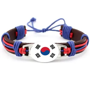 Dettaglio del braccialetto in pelle intrecciata con bandiera sudcoreana e cabochon
