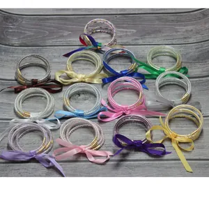 Juego de 5 brazaletes de silicona rellenos de perlas con lazos de cinta en varios colores.