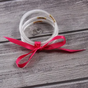 Detailed view of clear silicone glitter jelly bangles bundled with a pink ribbon bow