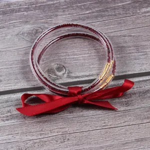 Detalle de los brazaletes de silicona de tres capas con diamantes rojos y cinta.