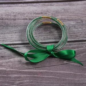 Detailed view of five layer green silicone jelly bangles with beads and green silk bow