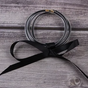 Détail de trois bracelets jelly pailletés transparents noués avec un ruban de satin noir