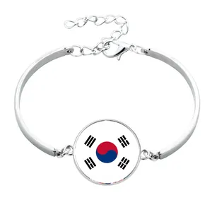Dettaglio macro di un braccialetto color argento con charm bandiera della Corea del Sud