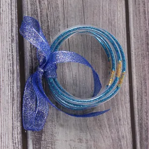 Detailopname van blauwe glitter siliconen armbanden vastgebonden met een decoratief lint