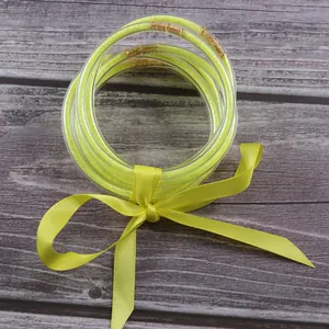 Close-up of neon yellow glitter jelly bangles tied with a matching satin ribbon.