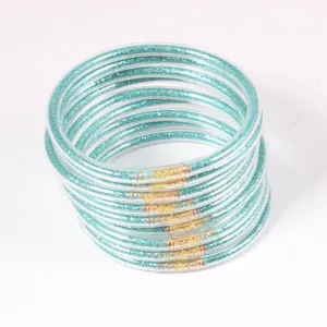 Macro detail of 12-piece teal glitter jelly bangles with gold finish tube connectors