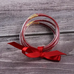 Set of 5 red seed bead silicone jelly bracelets decorated with a festive red ribbon bow.