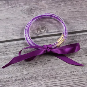 Vista detallada de pulseras jelly de silicona morada con purpurina y lazo de cinta