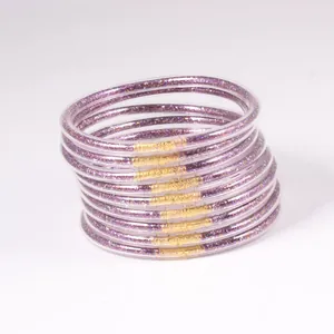 Close-up of stacked purple glitter jelly bangles with gold connectors.