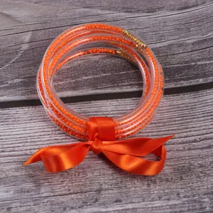 Set of five vibrant orange silicone bead bracelets tied with a matching satin ribbon bow