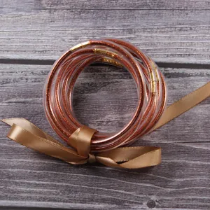 Detail view of seven layer silicone bangles with sparkling rose gold glitter and ribbon
