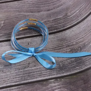 Close-up of 5-layer blue silicone jelly bangles with beads and a satin ribbon bow.