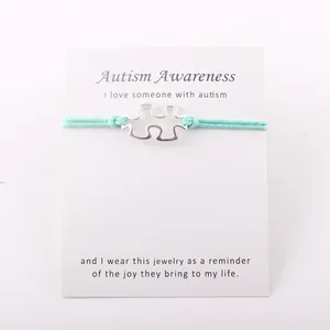 Detail van zilveren puzzelarmband voor autismebewustzijn met waskoord en cadeaubon