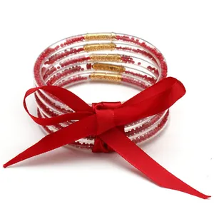Festive set of 5 red seed bead silicone bangles with a large red satin bow for women.