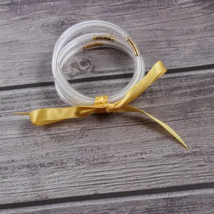 Set of clear glitter-filled jelly bangles with gold connectors and yellow ribbon