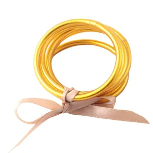 Elegant set of gold foil filled flexible silicone bangles tied with a pink ribbon bow