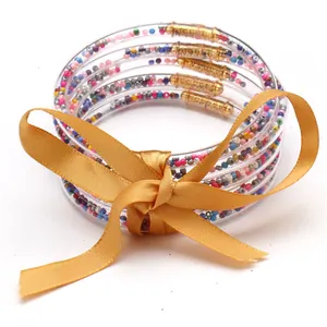 Primo piano di 5 bracciali in silicone con perline e fiocco in raso dorato
