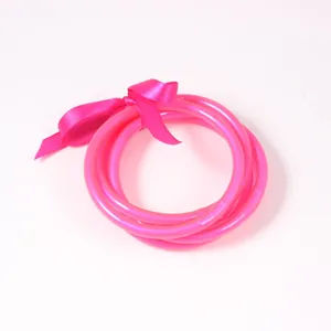 Neon pink jelly bangles set with a matching ribbon bow for a vibrant summer look.