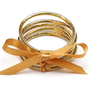 Close-up of five-piece gold glitter silicone jelly bangles with a matching ribbon bow.