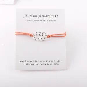 Autism Awareness verzilverde puzzelarmband op displaykaart met een oranje waskoord