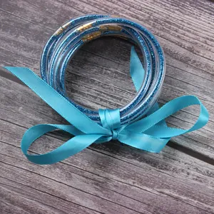 Detail view of seven blue glitter jelly bangles tied with a matching blue ribbon.